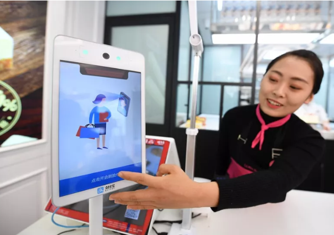 服務員在演示支付寶蜻蜓刷臉支付產(chǎn)品.png